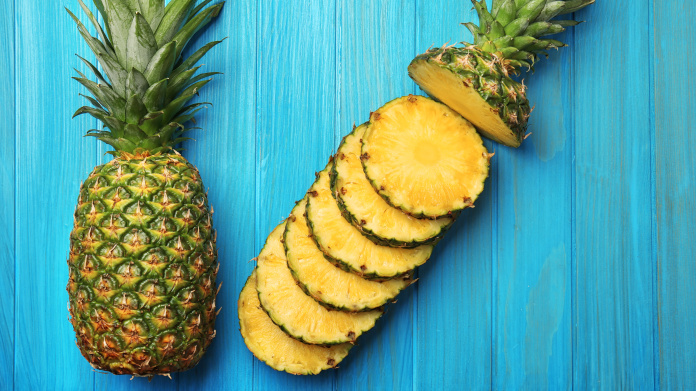 Ananas ricco di bromelina e tagliato su sfondo blu