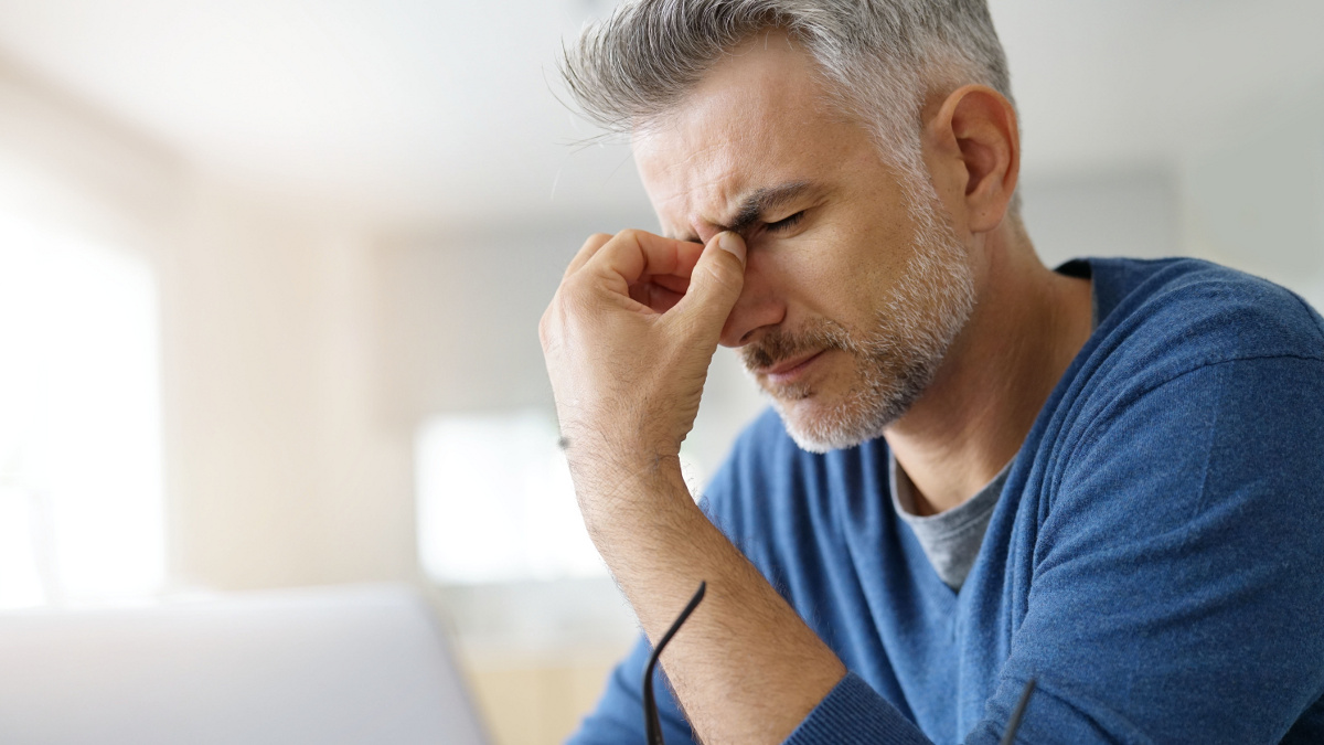 Man met hoofdpijn voor een computerscherm