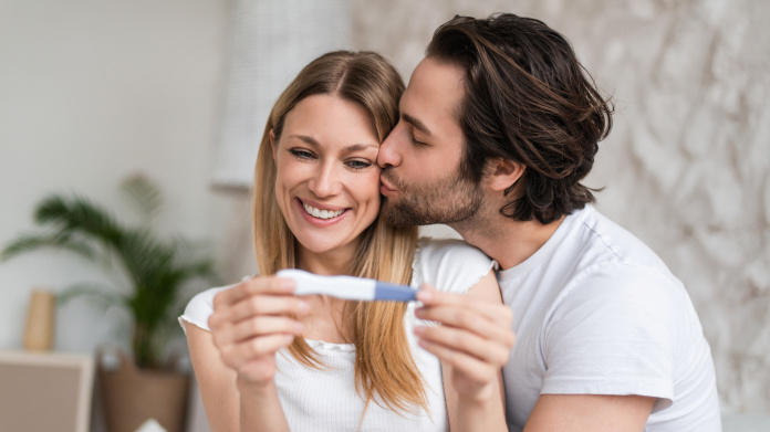 Casal fértil que observa um teste de gravidez positivo