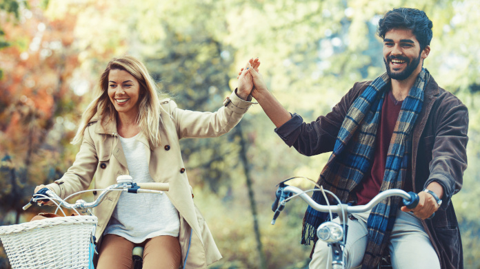 Casal cheio de energia a andar de bicicleta na floresta no outono