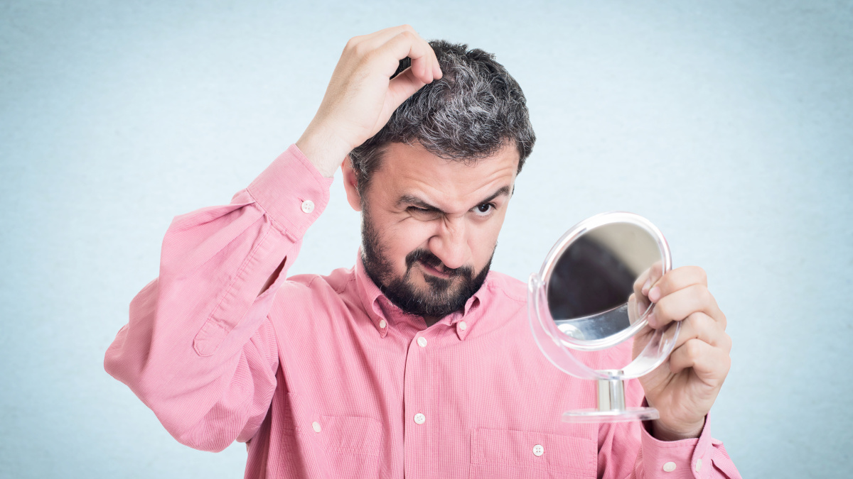 Man looking in the mirror seeing his hair going grey 