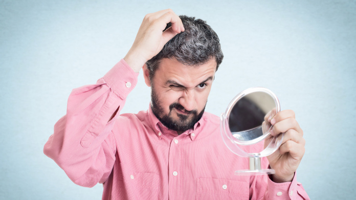 Uomo che vede i suoi capelli diventare bianchi allo specchio