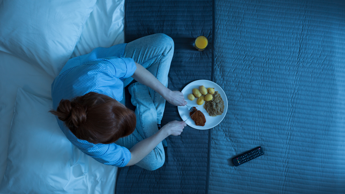 Frau, die nachts auf ihrem Bett isst