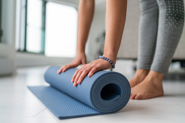 Frau rollt eine Yogamatte