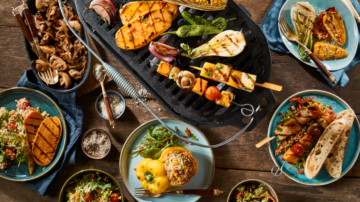 Churrasco vegetariano com legumes grelhados sobre uma mesa de madeira.